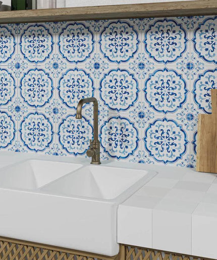 Kitchen with white sink, patterned blue tiles, and wooden cutting board.