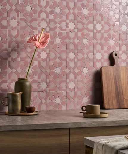 Decorative pink and gray tiled wall with a wooden cutting board, ceramic cups, and a vase.