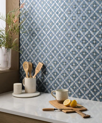 Kitchen counter with a mug, cutting board, and lemons against a patterned wall.