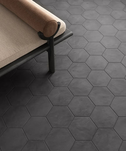 Hexagonal black tiles on a floor with a beige sofa.