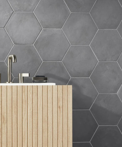 Hexagonal gray tiles on a wall with a wooden cabinet and silver fixtures.
