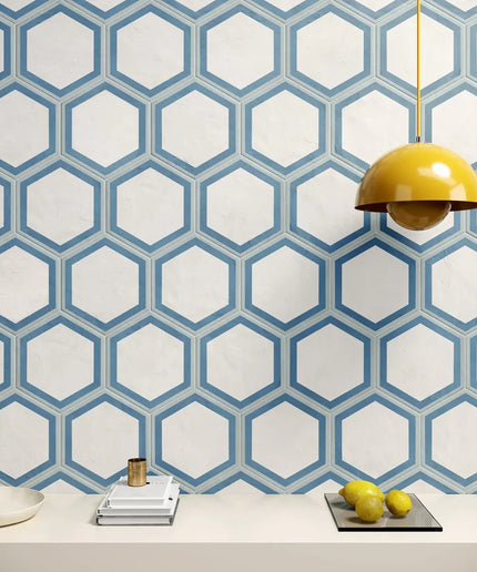Hexagonal patterned wallpaper with a yellow lamp and fruit on a table.