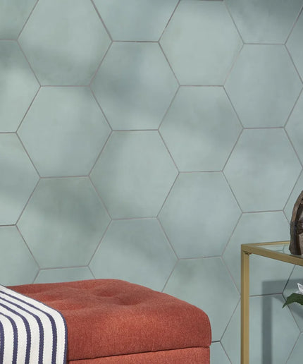 Hexagonal green tiles on a wall with a red cushion and striped blanket.