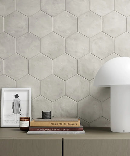 Hexagonal tile wall with a shelf displaying books, a candle, and a lamp.