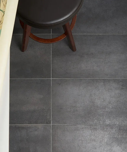 Dark gray tiles on a floor with a wooden stool and rolled-up map.