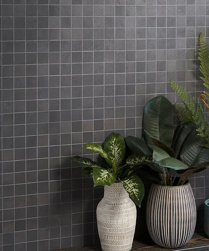 Three potted plants in front of a gray tiled wall