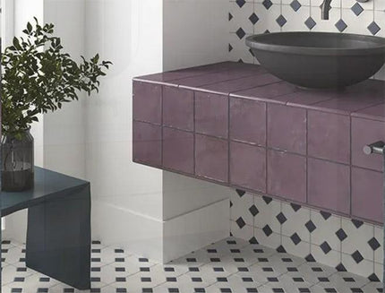 Bathroom with purple tiled vanity and black sink against a white wall with geometric tile pattern.