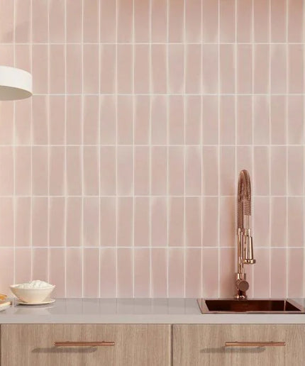 Kitchen with pink tiled wall and wooden cabinets
