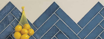 Bag of lemons and a banana on a blue tiled floor herringbone design