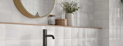 Bathroom with white tiled walls, wooden shelf, and decorative items.