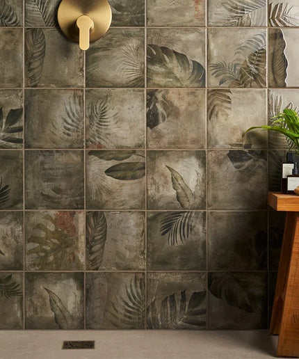 Bathroom with tiled wall featuring leaf patterns and a wooden stool with plants.