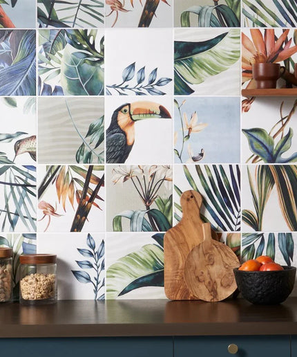 Tropical-themed kitchen backsplash with toucan and leaf patterns, wooden cutting board, and fruit bowl.