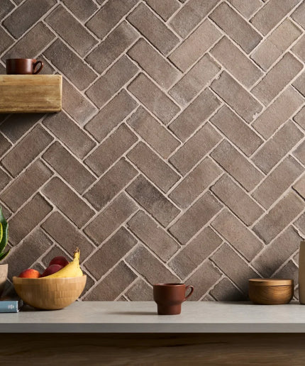 Herringbone patterned wall with decorative items on a shelf and table.