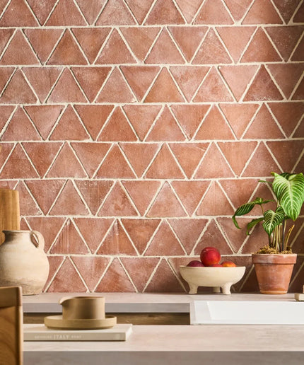 Kitchen with terracotta triangle-patterned tiles on the wall, wooden counter, and decorative items.