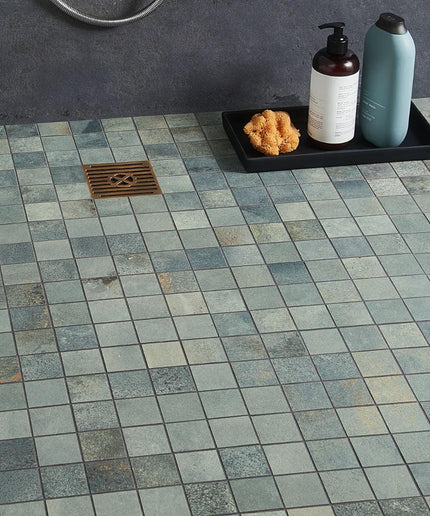 Tile floor with a shower drain and bath products on a tray