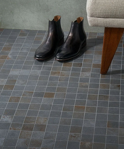 Pair of black leather boots on a tiled floor with a chair in the background