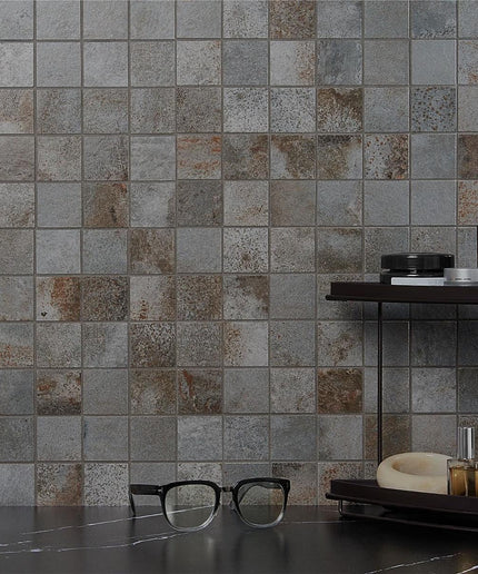 Mosaic tile wall with a dark countertop and glasses in front
