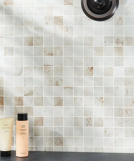 Two skincare products on a bathroom counter with a tiled wall background