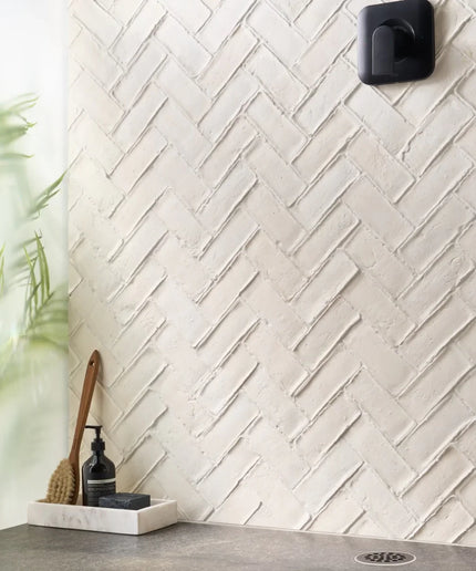 White tiled wall with a herringbone pattern in a bathroom setting.