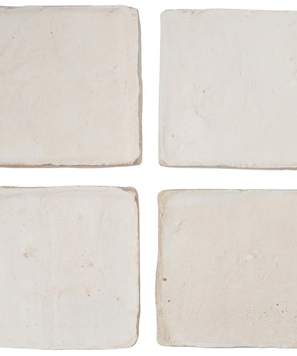 Four square beige coasters on a white background