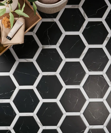 Hexagonal black and white tiles on a floor with a wooden tray and plants.