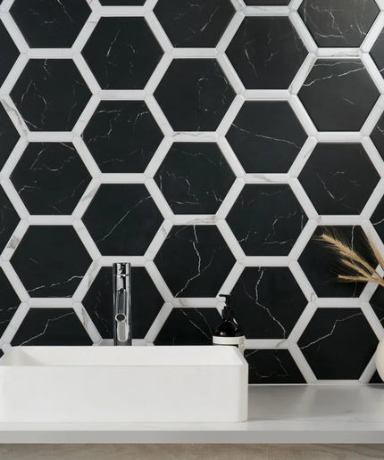 Bathroom with black hexagonal tiles on the wall, white sink, and decorative vase.