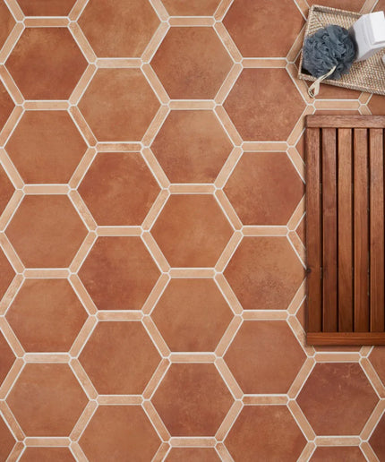 Hexagonal terracotta tiles on a floor with a wooden bench and cleaning supplies.