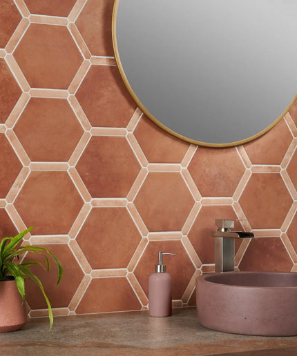 Bathroom with terracotta hexagonal tiles, a round mirror, and a sink.