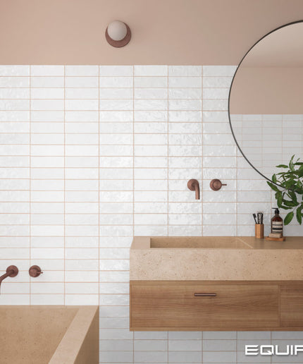 Bathroom interior with wooden vanity, round mirror, and tiled wall.