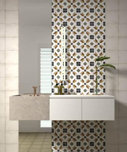 A modern bathroom vanity setup featuring a floating white cabinet, a stone sink basin, and a tall decorative tiled wall panel with a geometric pattern in black, white, and gold. A mirror is mounted above the sink, and a small potted plant sits on the right side.