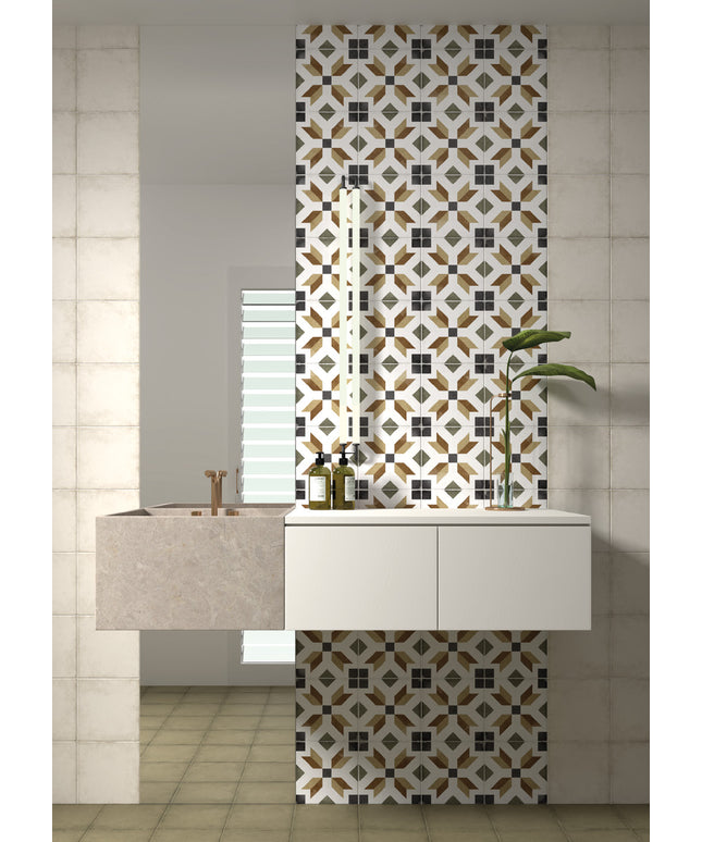 A modern bathroom vanity setup featuring a floating white cabinet, a stone sink basin, and a tall decorative tiled wall panel with a geometric pattern in black, white, and gold. A mirror is mounted above the sink, and a small potted plant sits on the right side.
