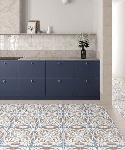 A modern kitchen interior featuring navy blue cabinets, a light stone countertop, and a patterned blue, white, and beige tile floor.
