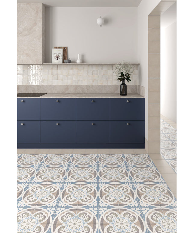 A modern kitchen interior featuring navy blue cabinets, a light stone countertop, and a patterned blue, white, and beige tile floor.