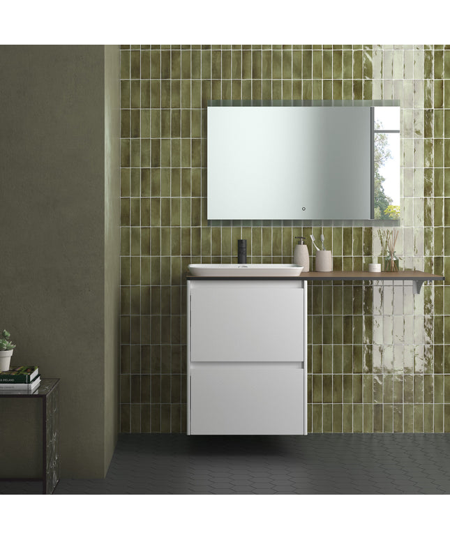 A modern bathroom vanity setup with a white two-drawer cabinet, a white rectangular basin, a dark wood-look countertop, a wall-mounted mirror, and glossy green tile wall behind it.