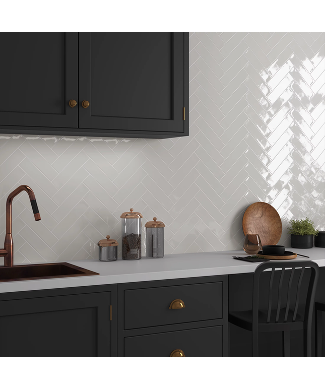 Modern kitchen with white herringbone tile backsplash, black cabinets, and copper accents.