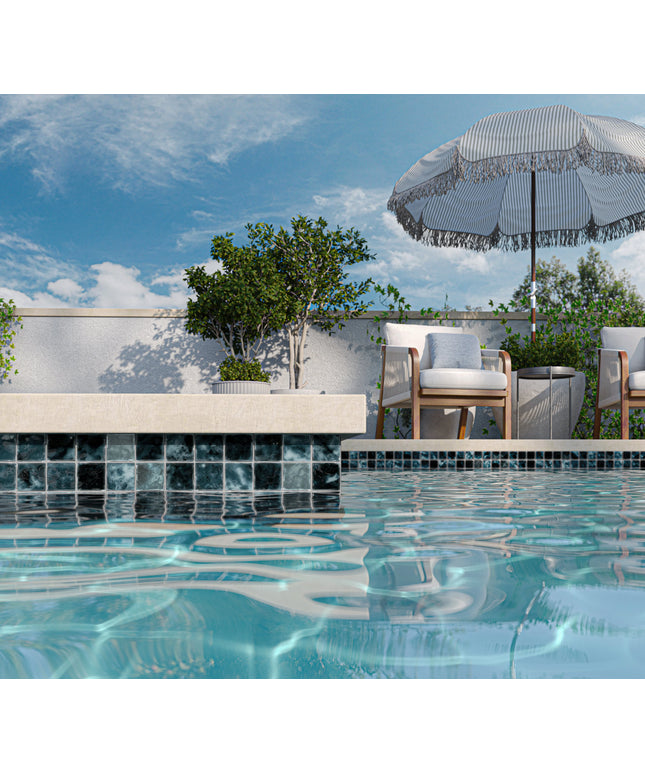 Pool area with lounge chairs, umbrella, and trees under a blue sky.
