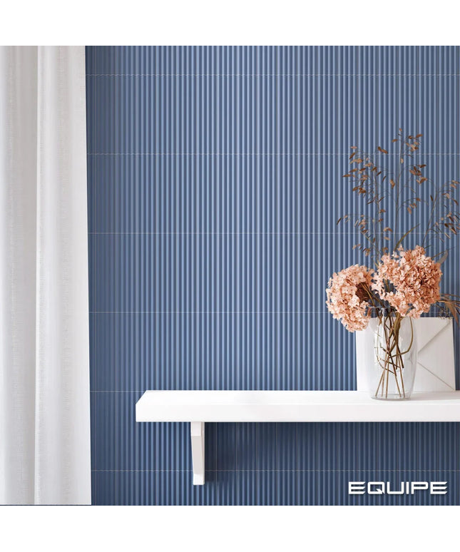 Blue ribbed wall paneling with a white floating shelf and vase of dried flowers, shown in a styled interior setting with the brand name EQUIPE in the bottom right corner.