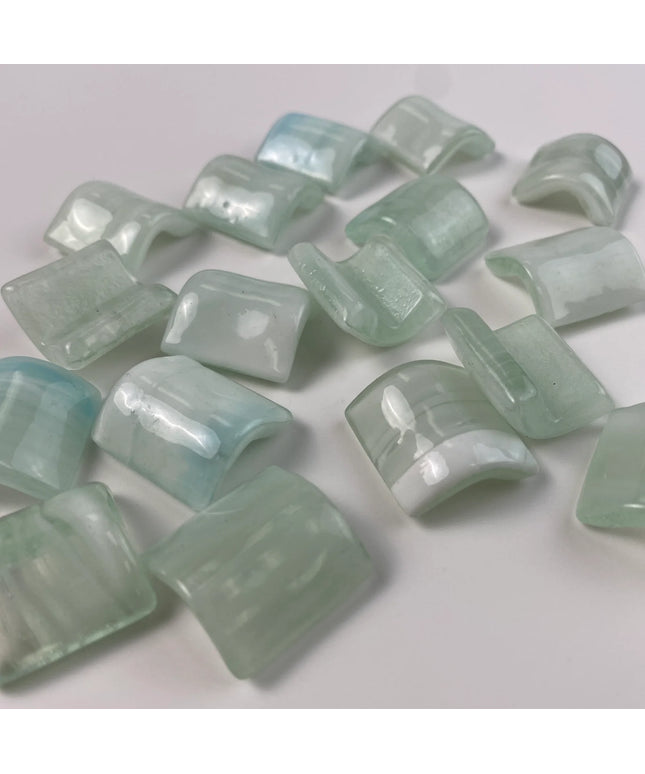 Glossy light green glass mosaic tiles with curved shapes on a white background