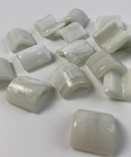 Glossy white curved glass mosaic tile pieces on a white background