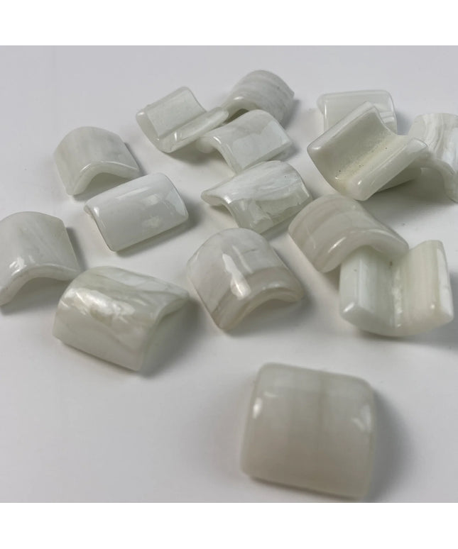 Glossy white curved glass mosaic tile pieces on a white background