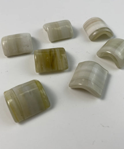 Curved beige and cream mosaic tile pieces on a white background, ideal for backsplash or decor.