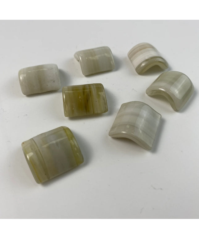 Curved beige and cream mosaic tile pieces on a white background, ideal for backsplash or decor.