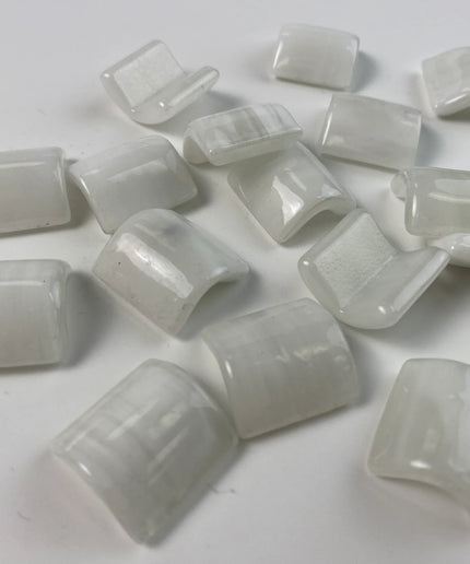 Glossy white curved glass mosaic tiles on a plain background, ideal for backsplash or bathroom decor.