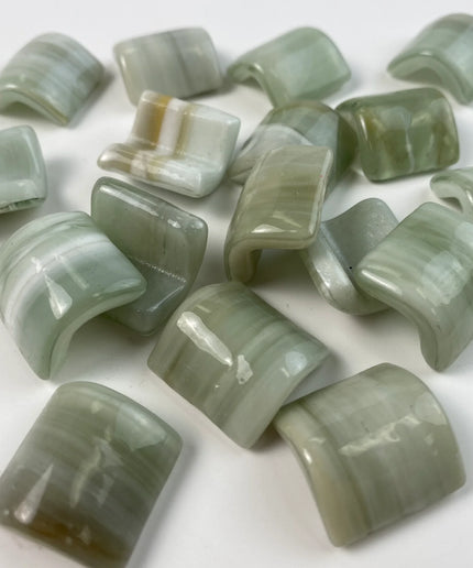 Glossy curved mosaic glass tiles in light green shades on a white background