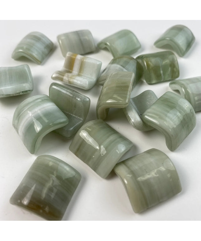 Glossy curved mosaic glass tiles in light green shades on a white background