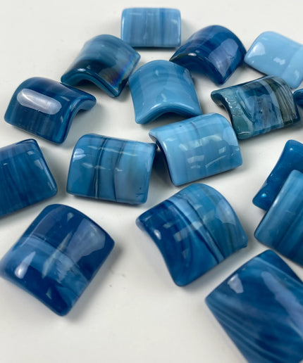 Glossy blue glass mosaic tiles with curved surfaces on a white background