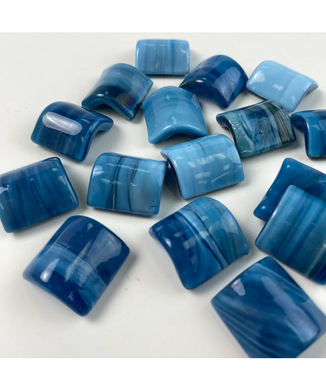 Glossy blue glass mosaic tiles with curved surfaces on a white background