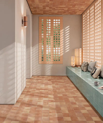 A modern interior space with terracotta checkered floor tiles, a built-in bench with gray cushions, and warm wood lattice screens on the walls and ceiling.