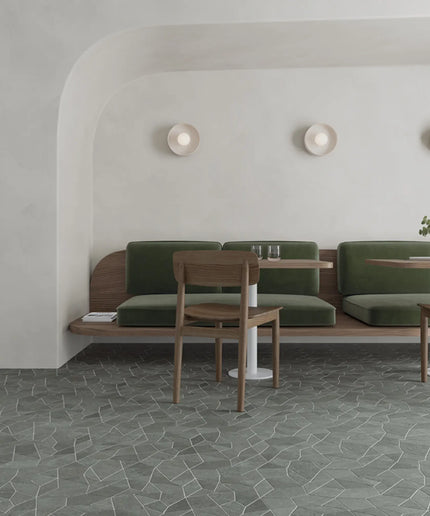Modern interior with green cushioned bench and wooden chairs against a white wall.