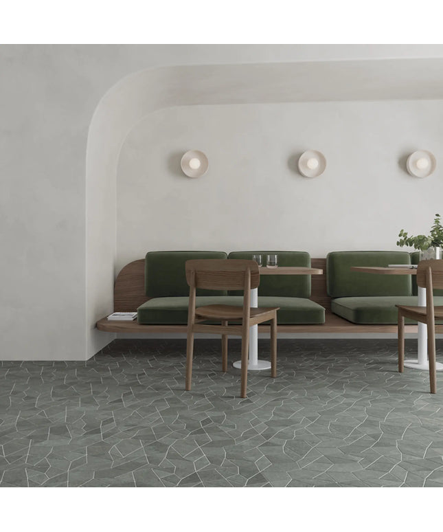 Modern interior with green cushioned bench and wooden chairs against a white wall.